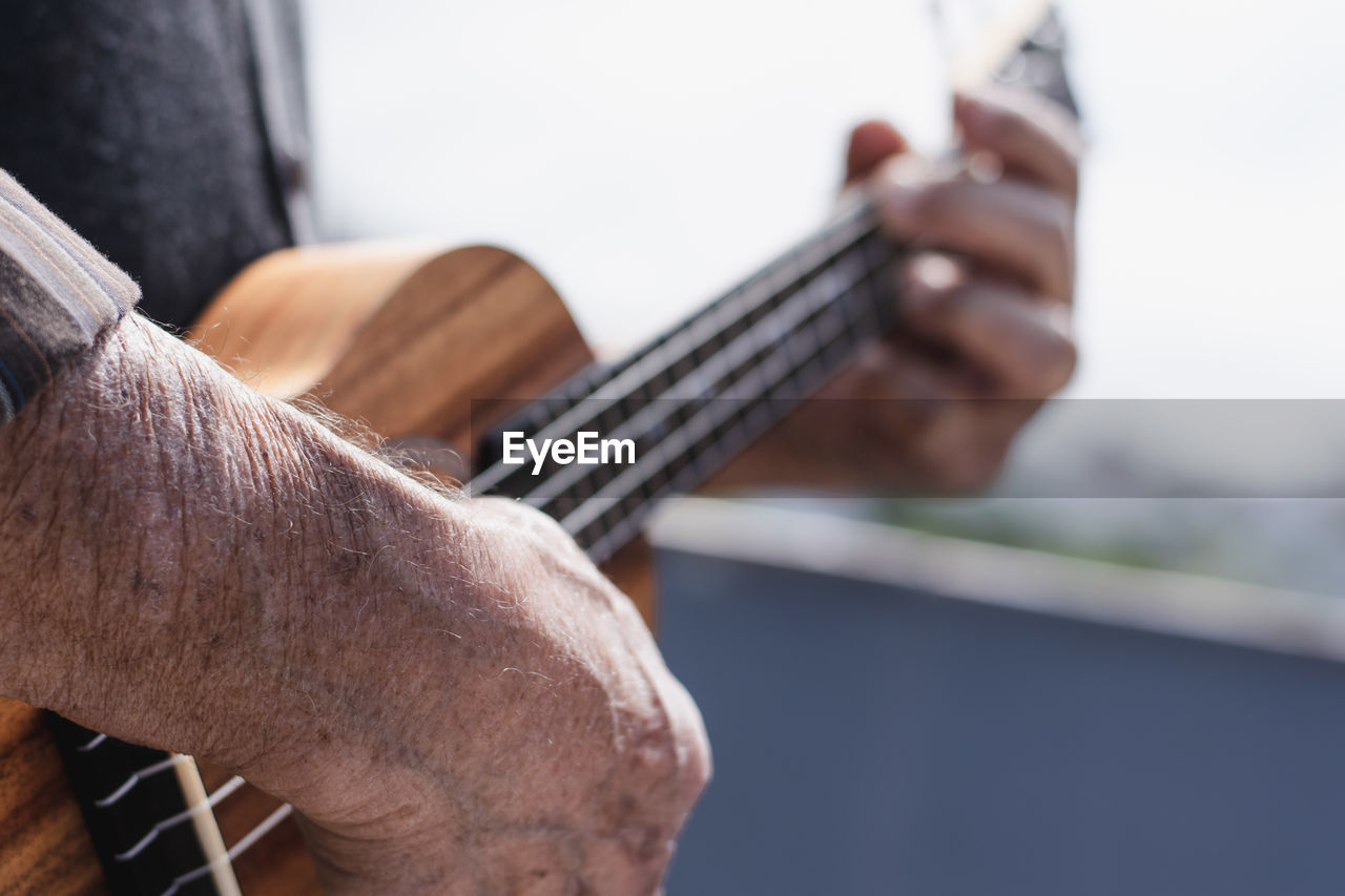 Midsection of man playing guitar