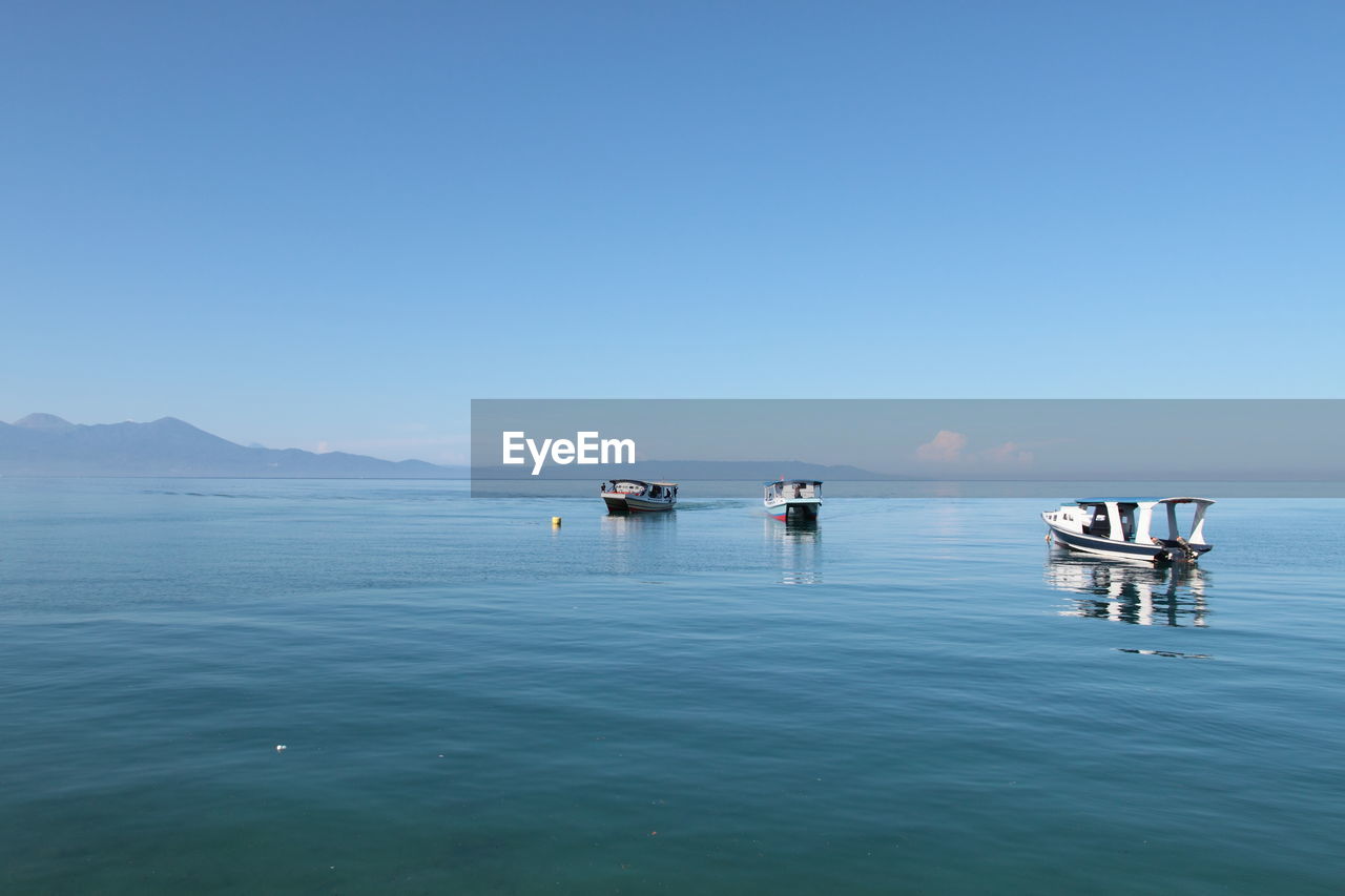 Scenic view of empty motorboats and sulawesi sea against clear sky