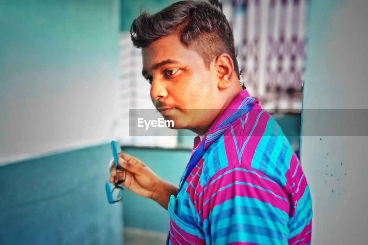 Man looking away while standing against wall