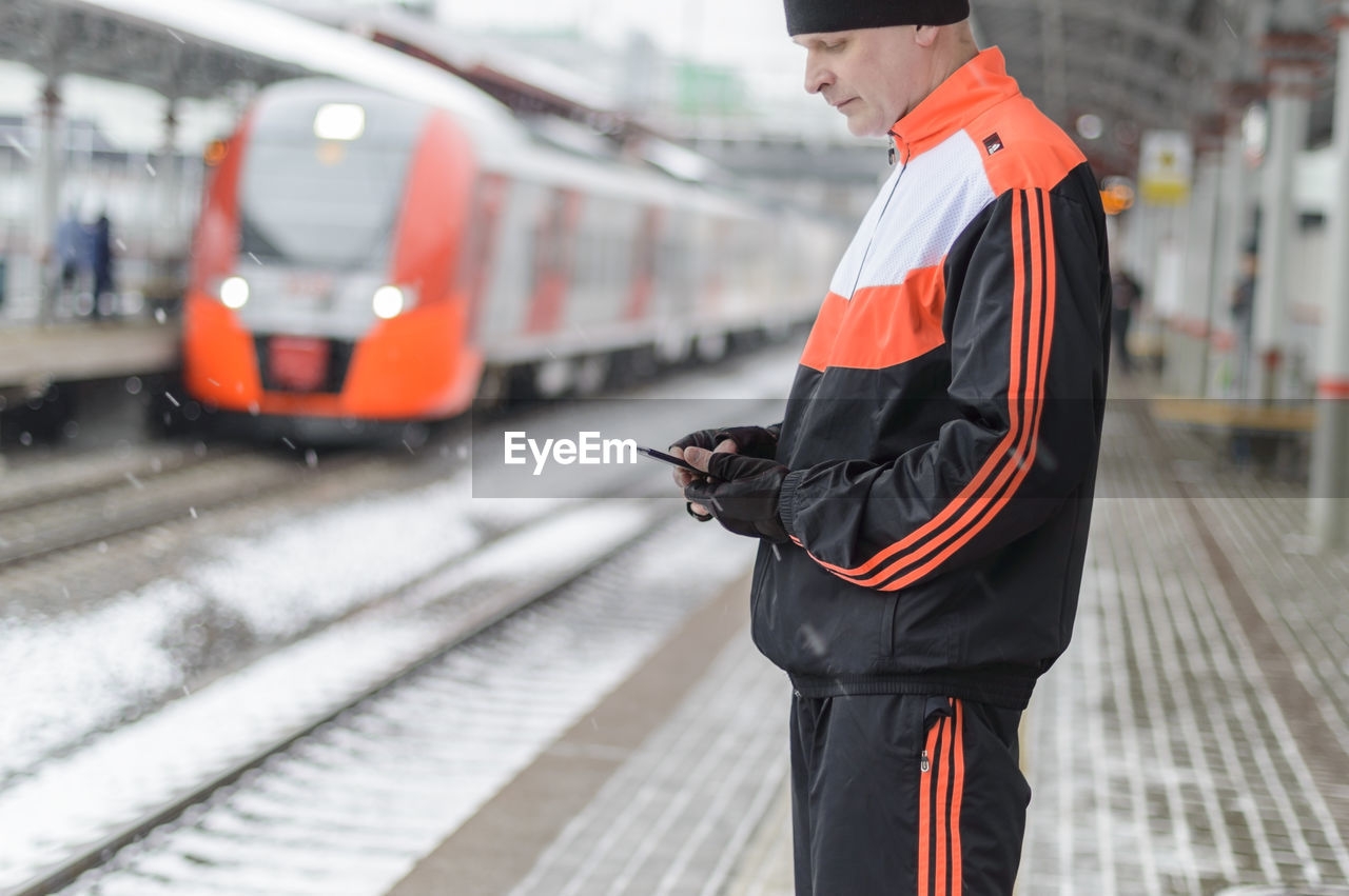 REAR VIEW OF MAN STANDING ON TRAIN