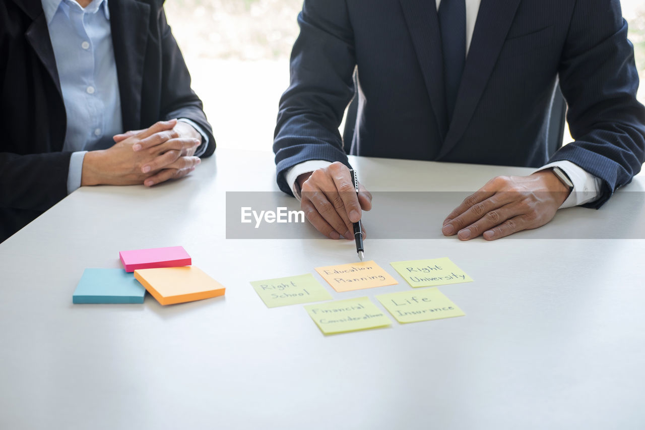 midsection of business colleagues working on desk in office