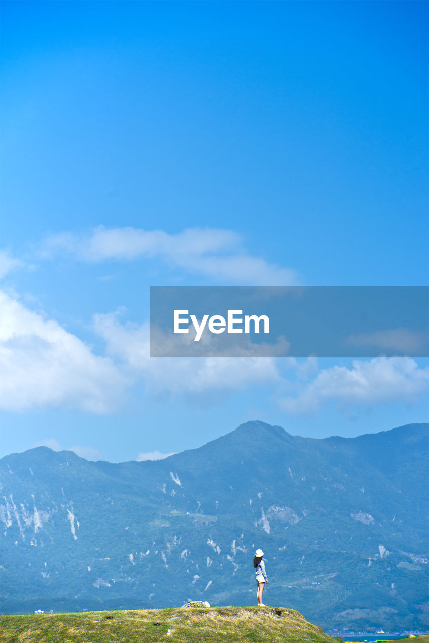 Woman standing on mountain against sky