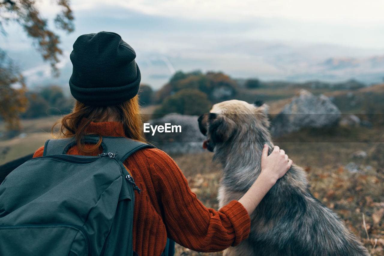 REAR VIEW OF WOMAN WITH DOG IN WINTER