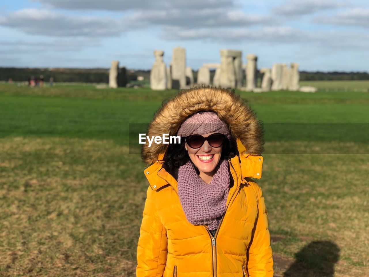 Smiling young woman standing against stonehenge