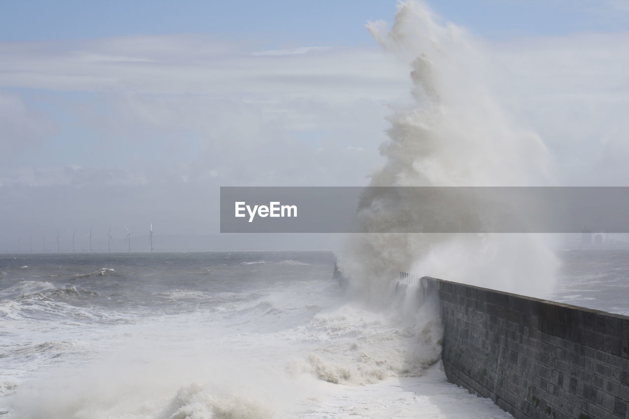 Waves splashing on sea against sky