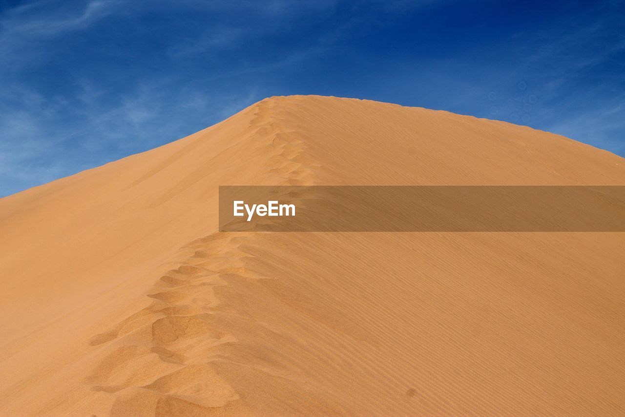 Sand dune in sahara desert against blue sky