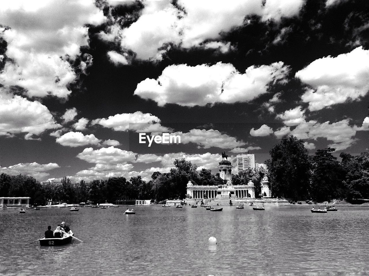 People in boat on lake against cloudy sky