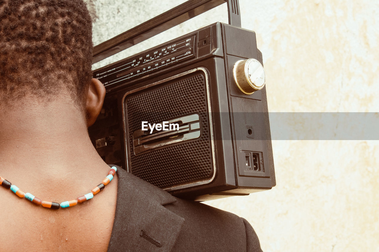 Close-up of young man with vintage radio against wall