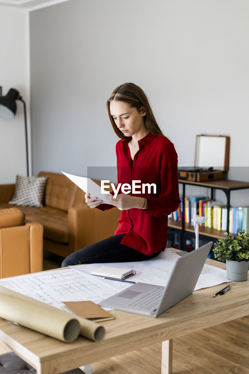 Woman in office holding paper with wind turbine model on table