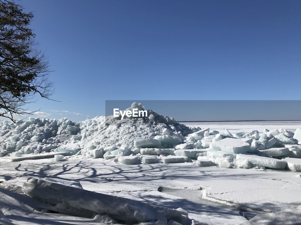 Snow covered landscape against clear blue sky
