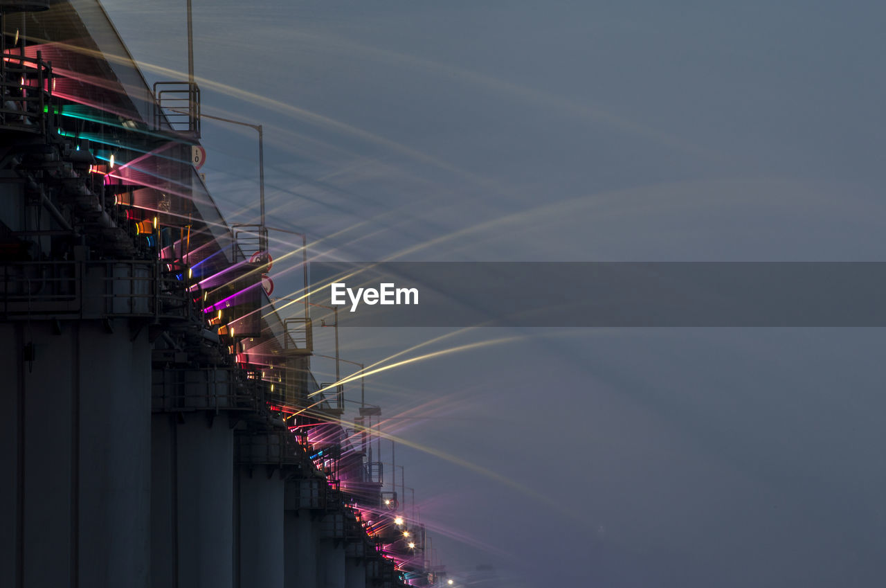 Low angle view of water flowing from bridge against sky at dusk