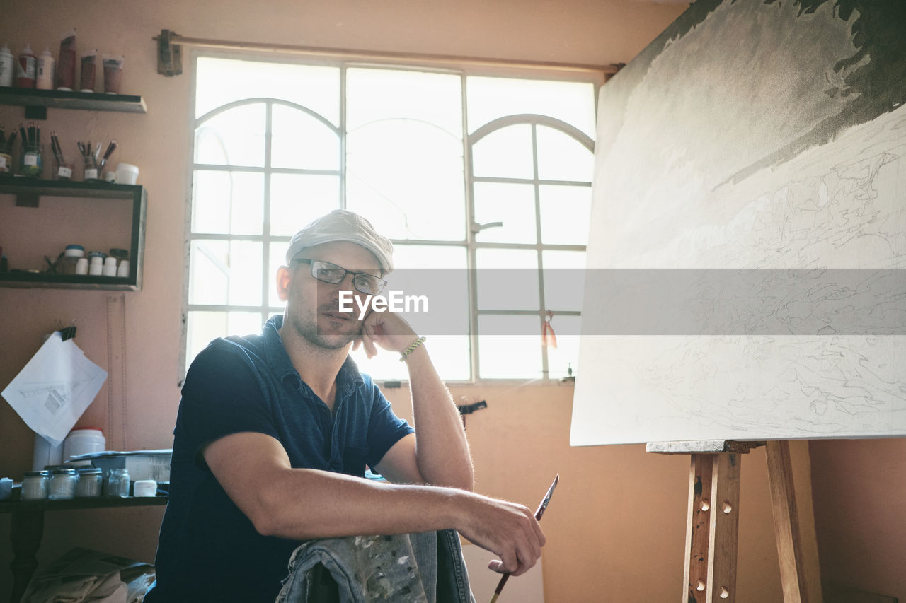 Portrait of man working as painter holding brush in workshop