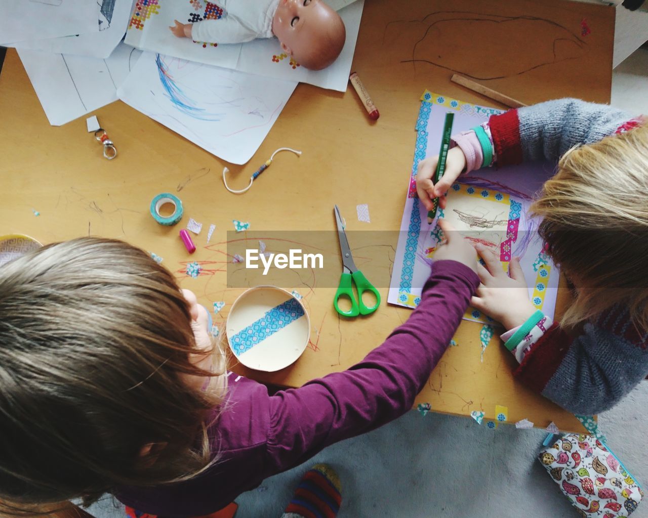 High angle view of siblings drawing on table