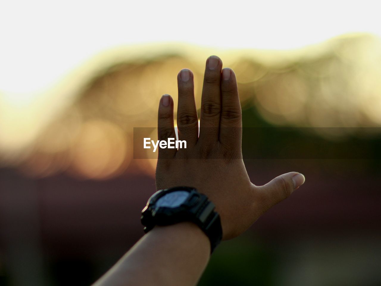 Cropped hand on man stop gesture during sunset
