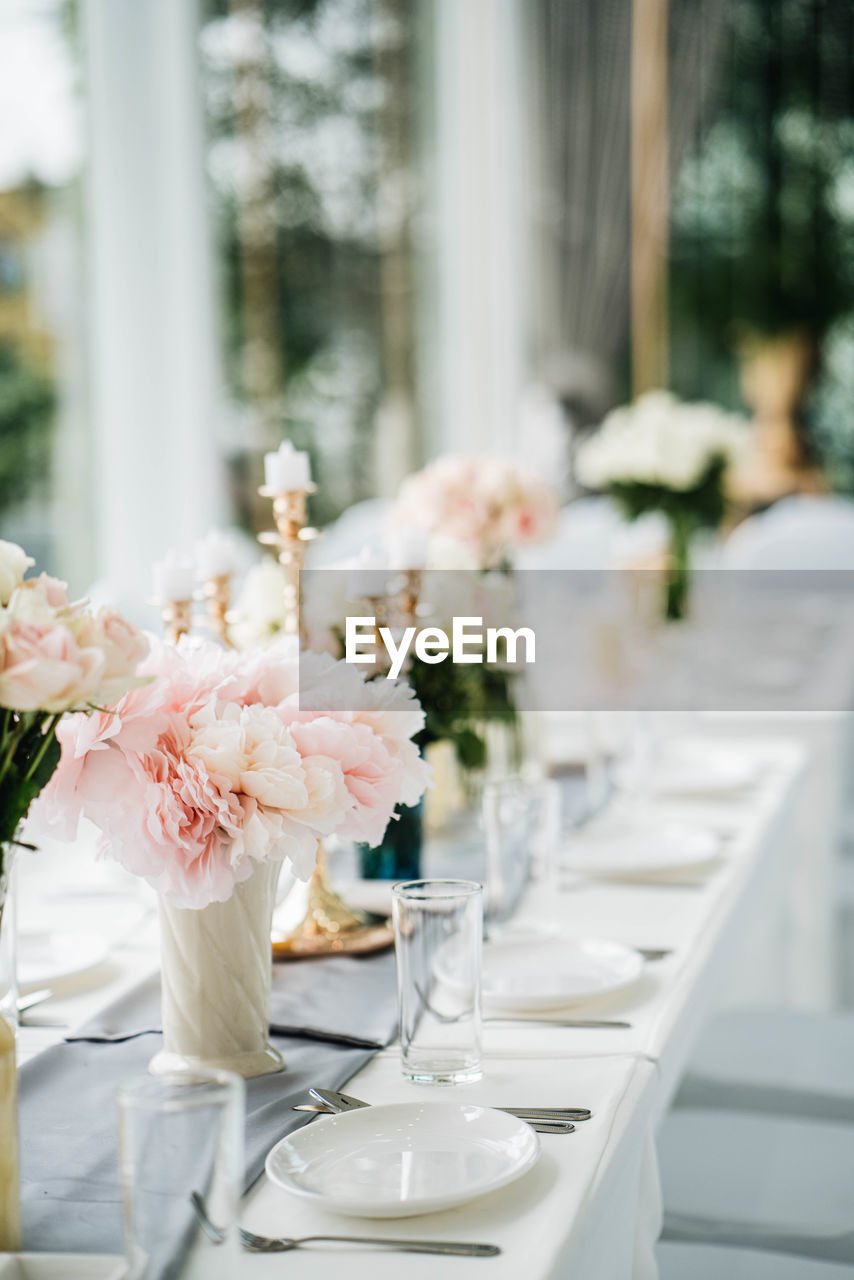 White long set wedding dinner table with decoration candlestick, glasses, and flowers. selective foc