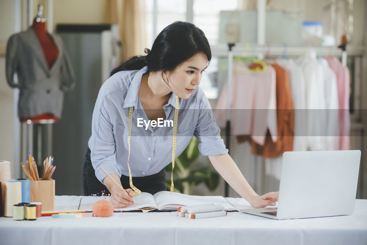 Young fashion designer using laptop at boutique