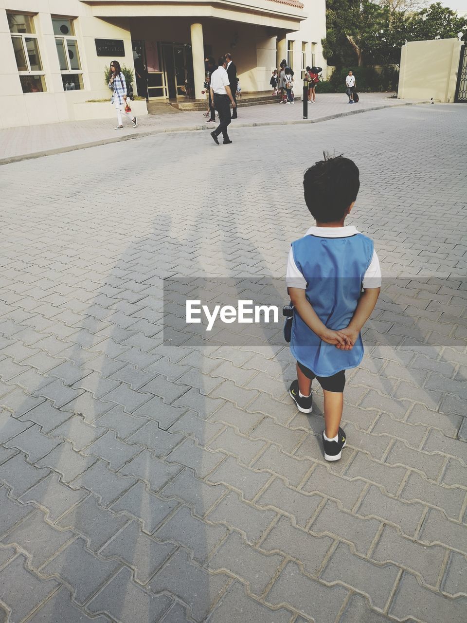 REAR VIEW OF BOY WALKING ON FOOTPATH IN STREET