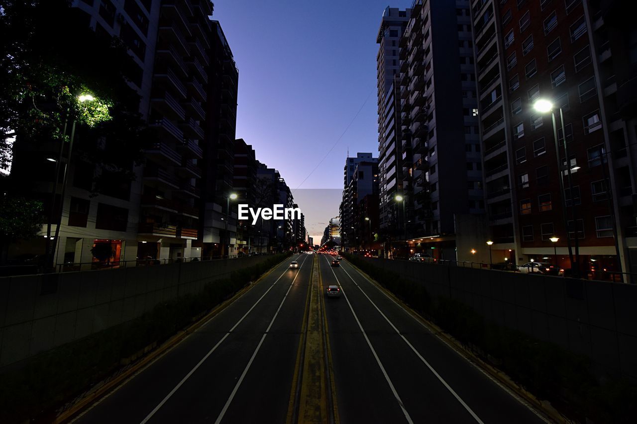 Road passing through illuminated city at night