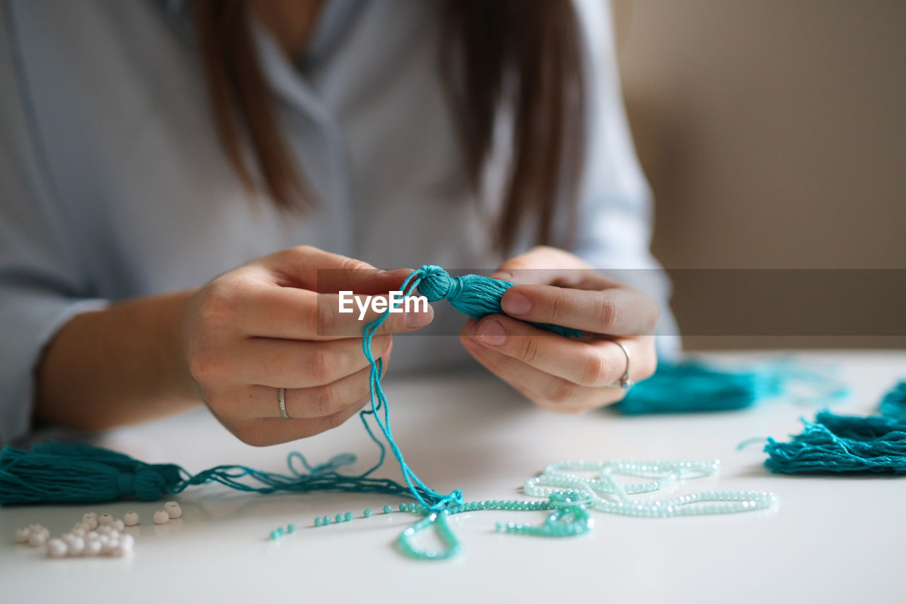 Woman working with threads and beads close-up, concept creativity, hobby and small business.