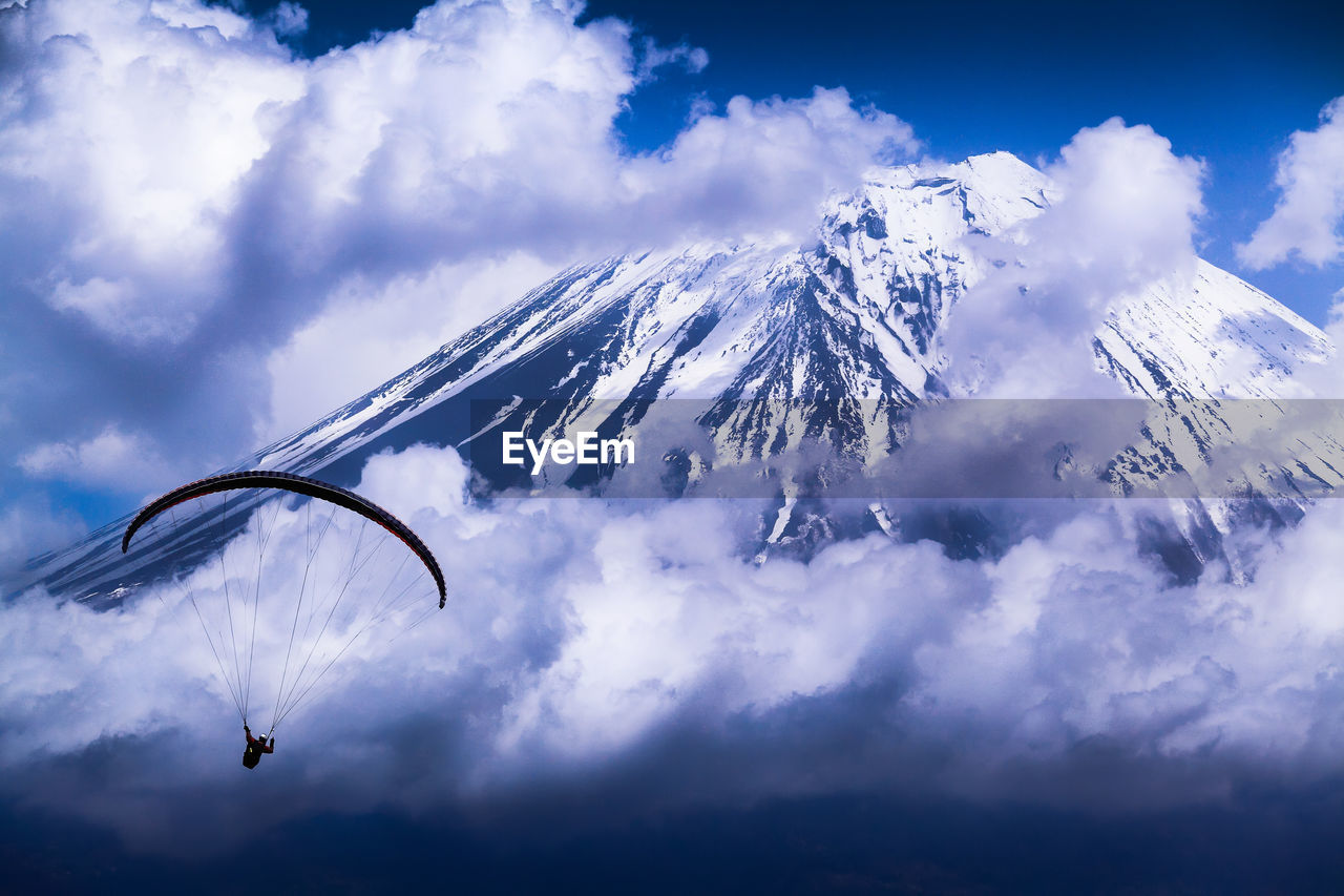 LOW ANGLE VIEW OF PEOPLE ON SNOWCAPPED MOUNTAIN AGAINST SKY