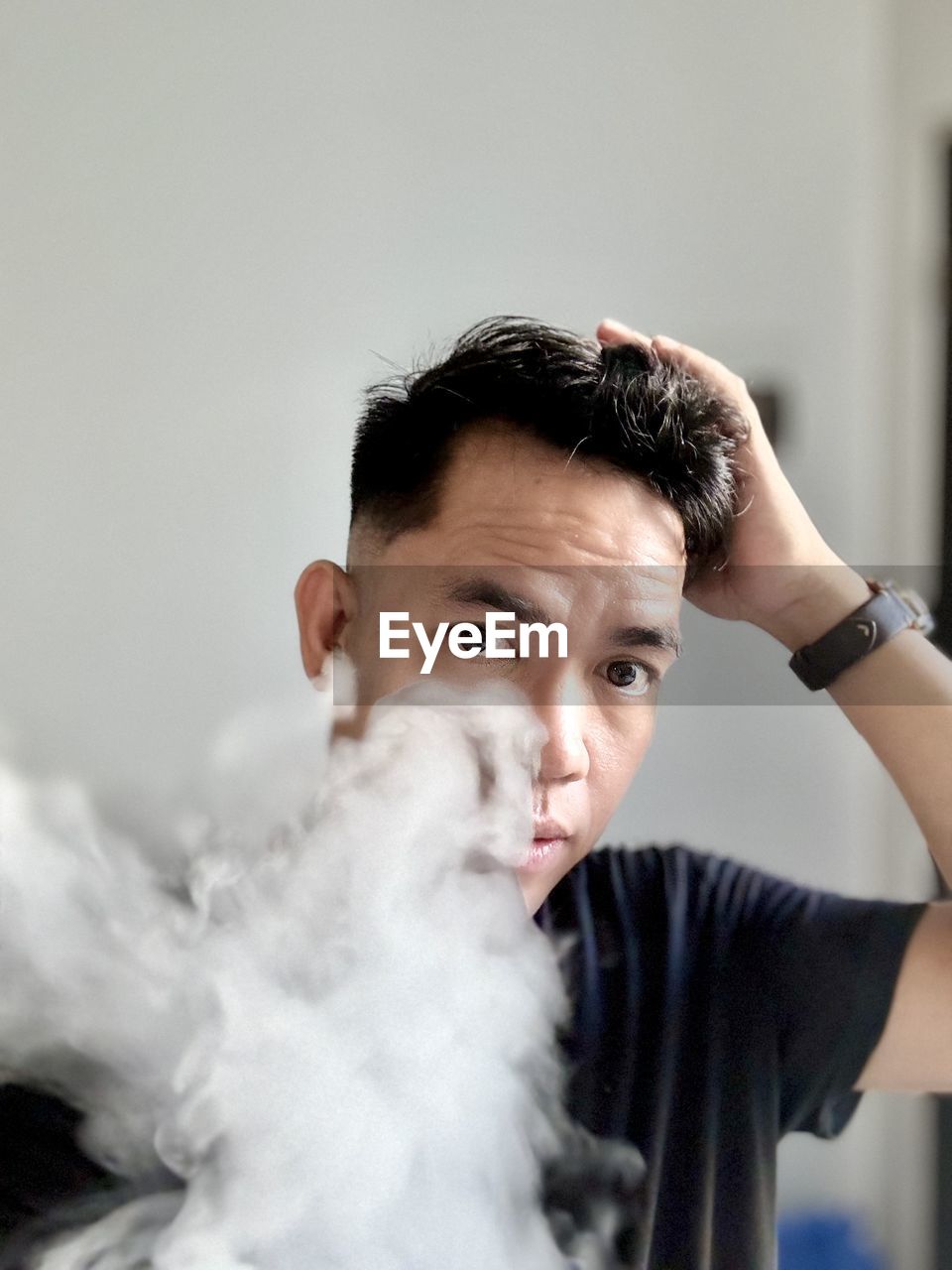 Portrait of smiling young man looking at the camera with smoke