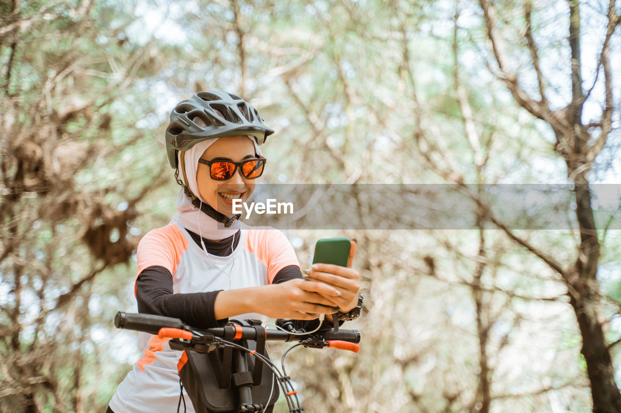 Young woman listening music on bicycle