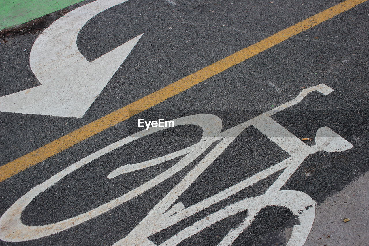 High angle view of arrow and bicycle lane sign on road