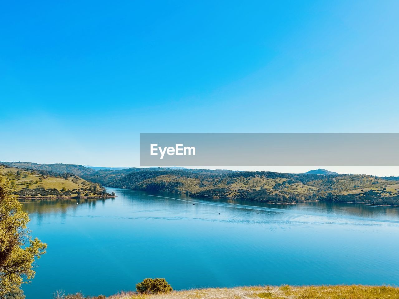 Scenic view of lake against clear blue sky