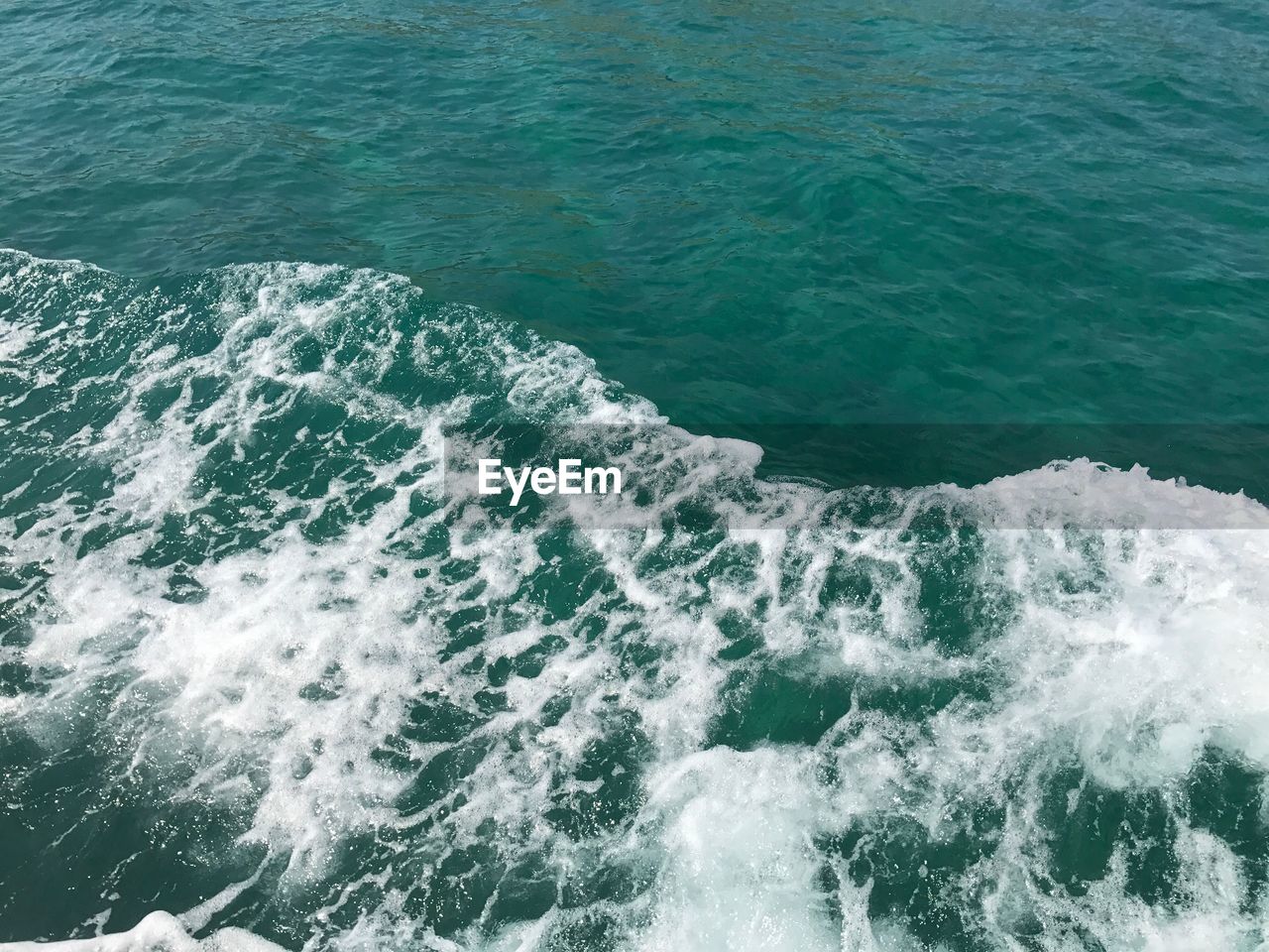 HIGH ANGLE VIEW OF WAVES BREAKING AGAINST SEA