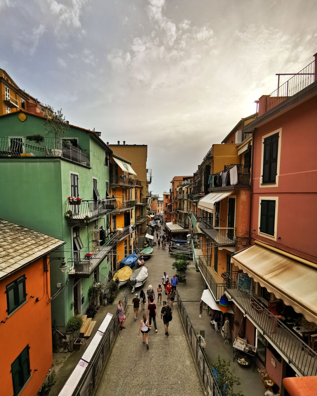 PEOPLE WALKING ON STREET AMIDST BUILDINGS AGAINST SKY