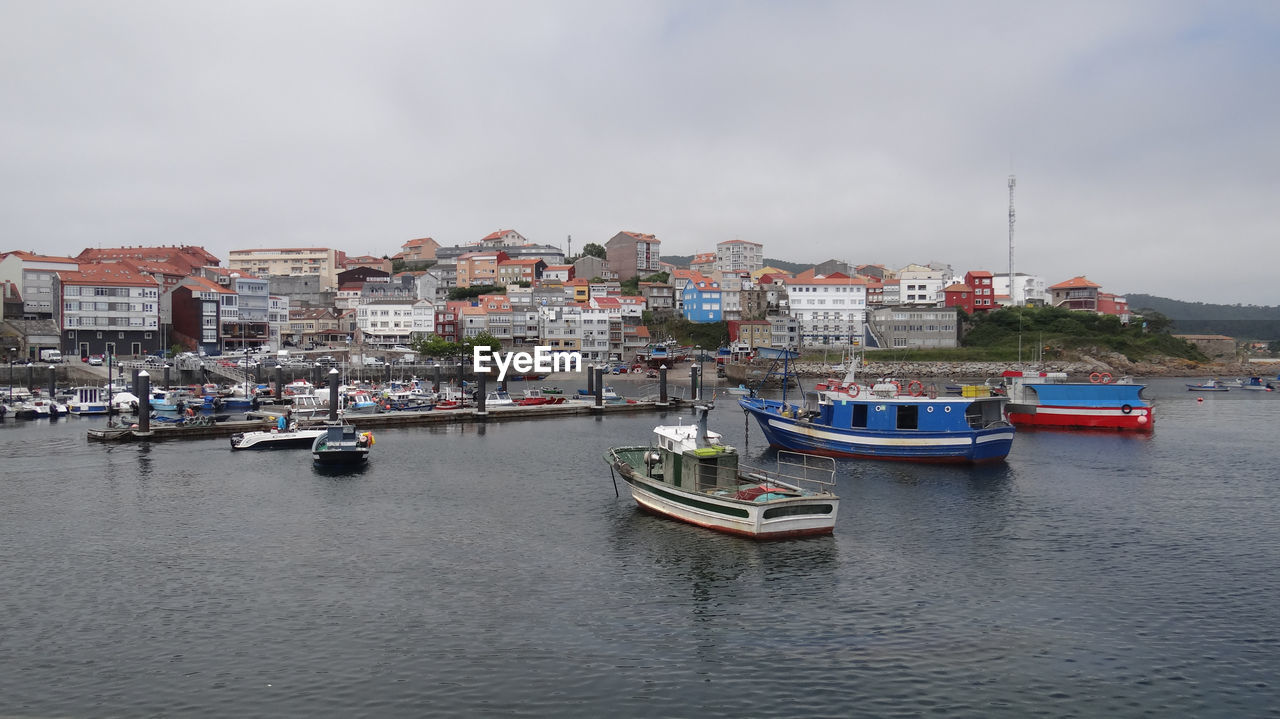 Boats moored in sea against buildings in city