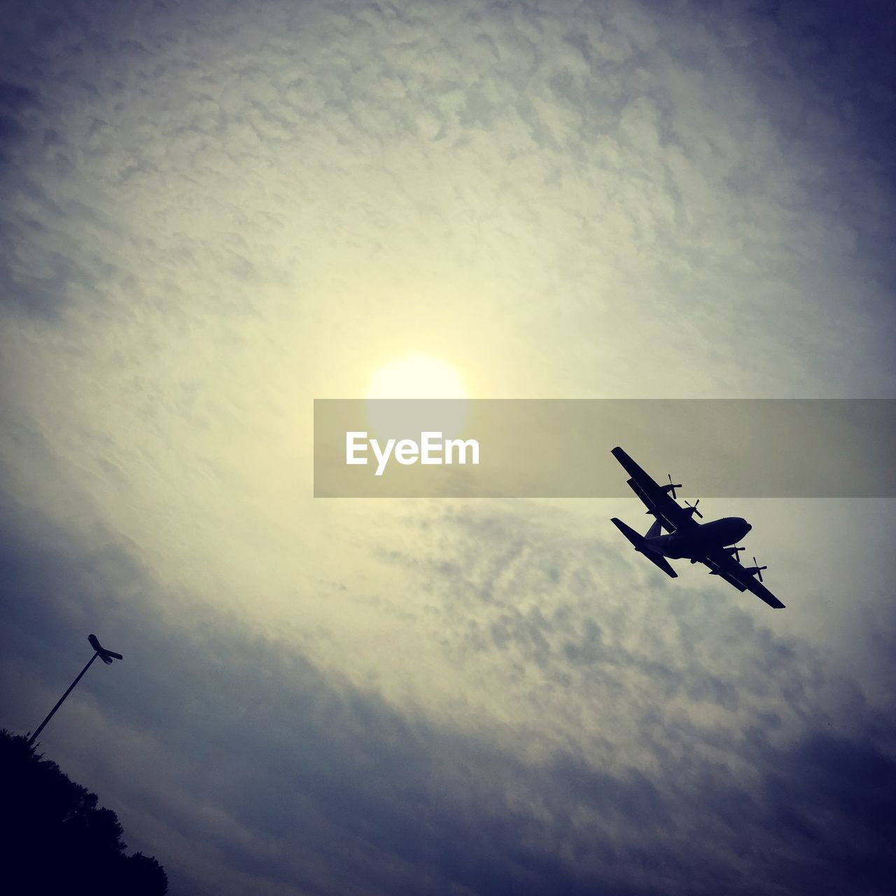 Low angle view of airplane flying in cloudy sky