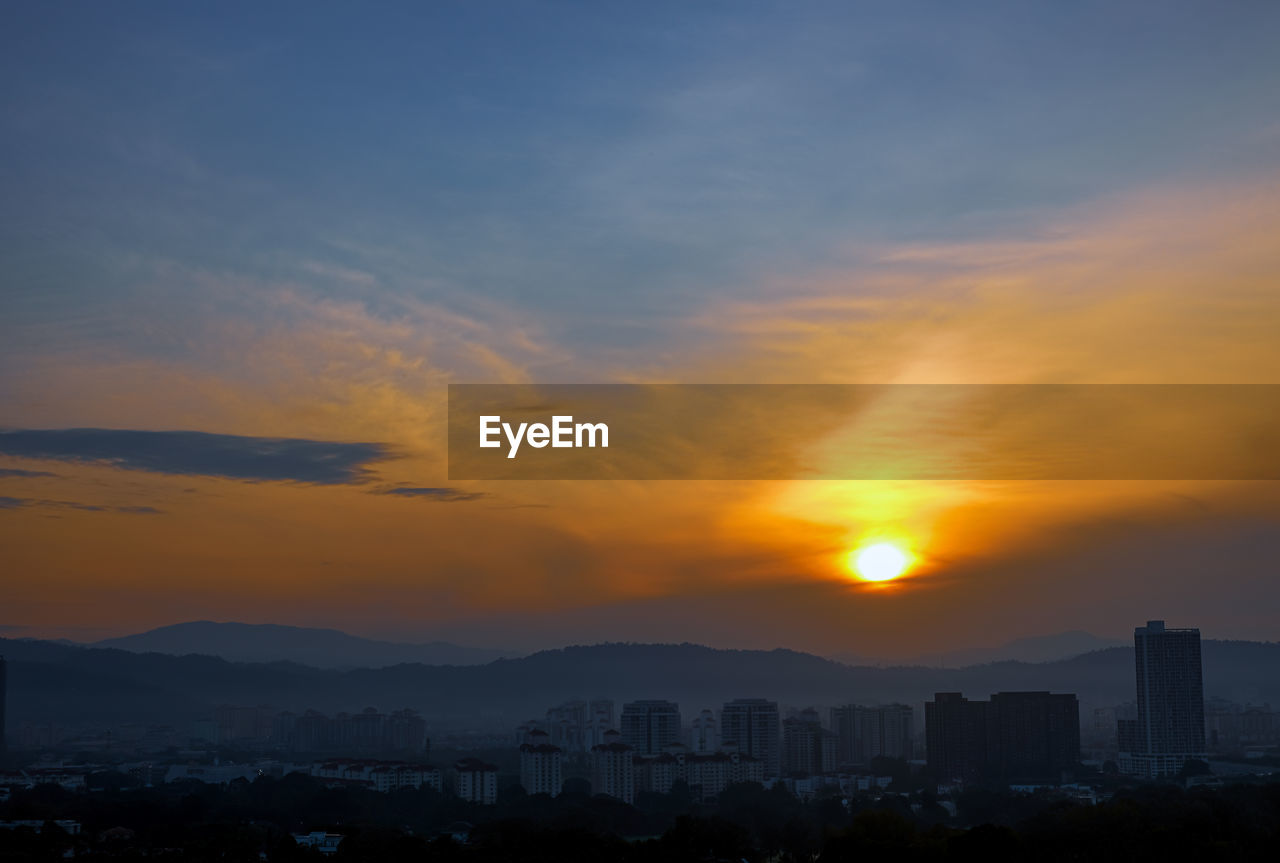 SILHOUETTE BUILDINGS AGAINST ORANGE SKY