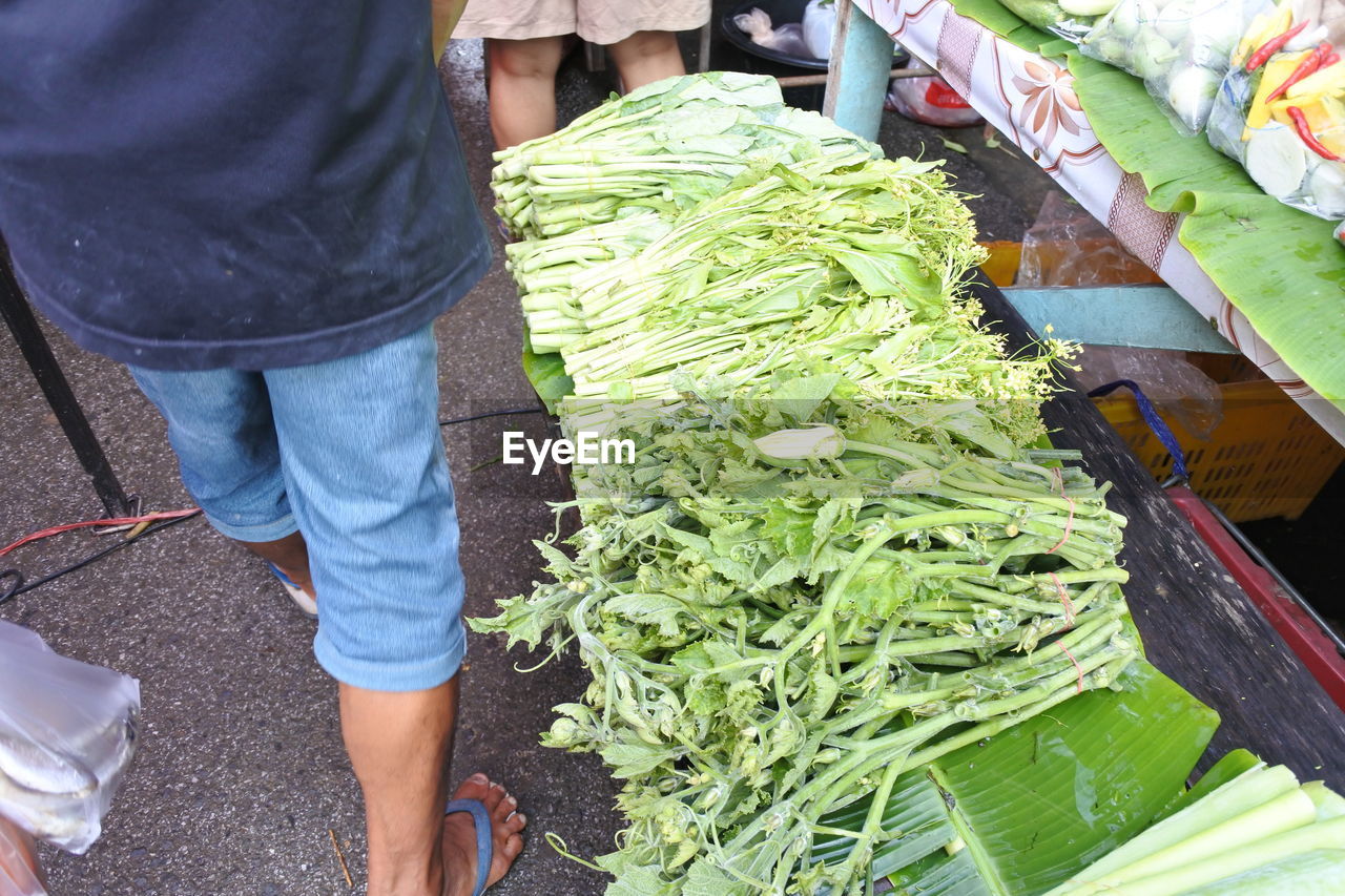 LOW SECTION OF PERSON WITH VEGETABLES FOR SALE AT MARKET