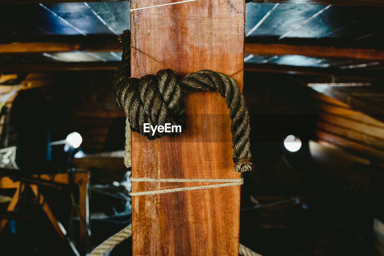 CLOSE-UP OF ROPE TIED TO WOODEN POSTS
