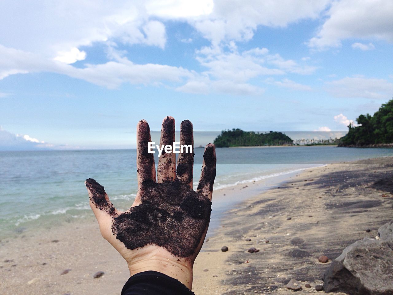 Close-up of messy hand at beach against sky