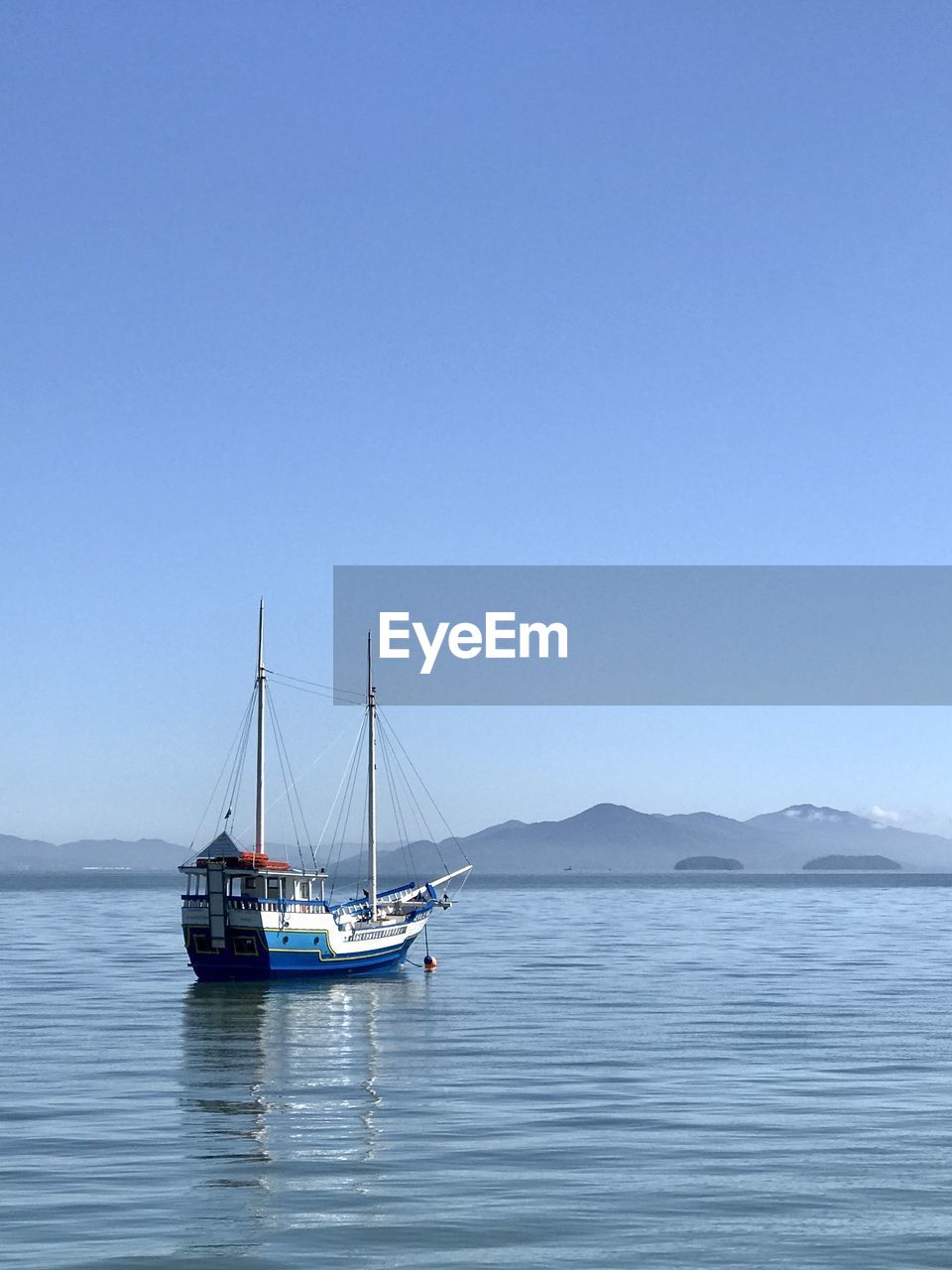 water, nautical vessel, transportation, sea, mode of transportation, sky, sailboat, travel, blue, sailing, vehicle, nature, boat, beauty in nature, clear sky, scenics - nature, tranquility, tranquil scene, bay, ship, copy space, travel destinations, sailing ship, no people, day, pole, idyllic, mast, holiday, environment, mountain, vacation, outdoors, tourism, trip, non-urban scene, ocean, watercraft, sunny, land, landscape, beach, horizon
