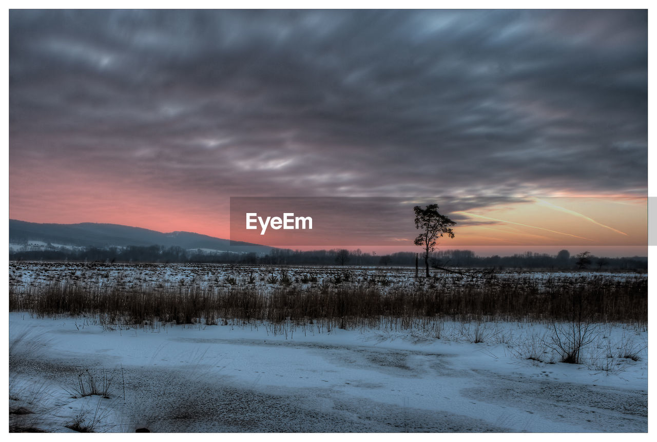 SCENIC VIEW OF SNOWY FIELD AGAINST SKY DURING SUNSET