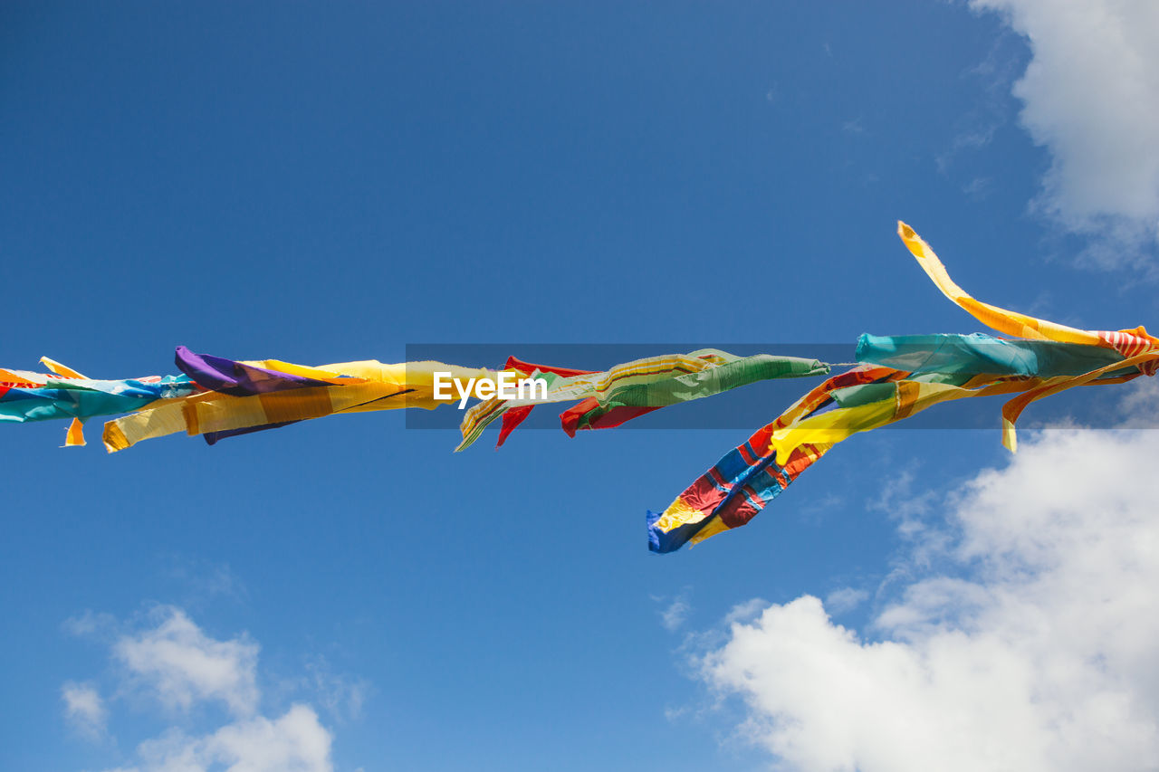 Low angle view of multi colored flags hanging against sky