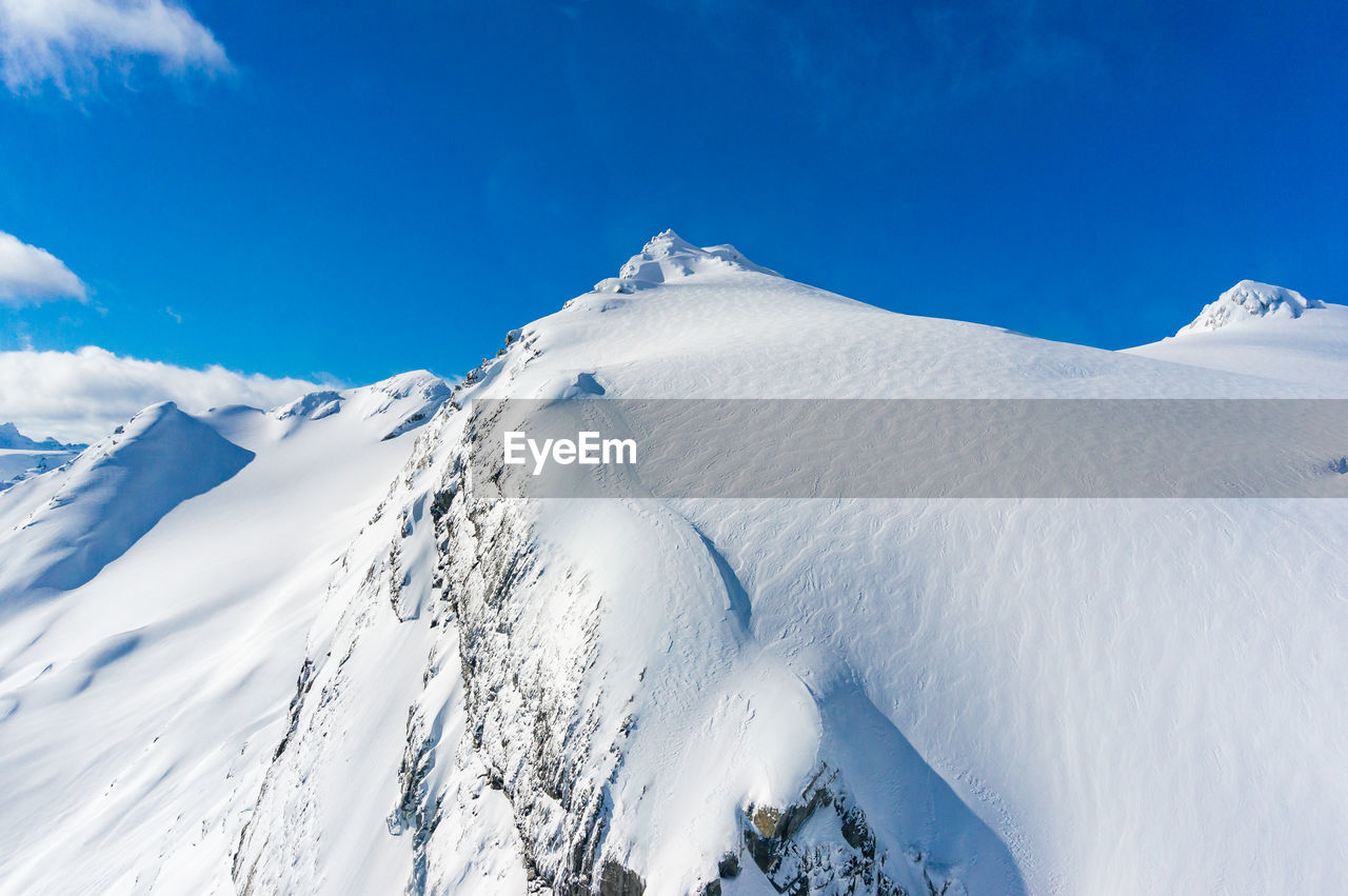 Scenic view of snowcapped mountains against blue sky