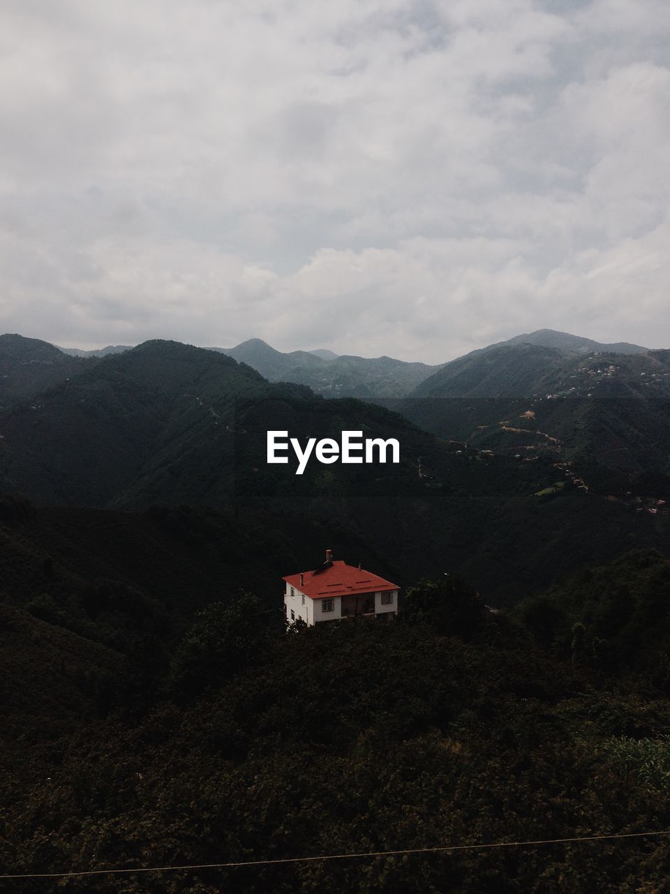 House on mountain against cloudy sky