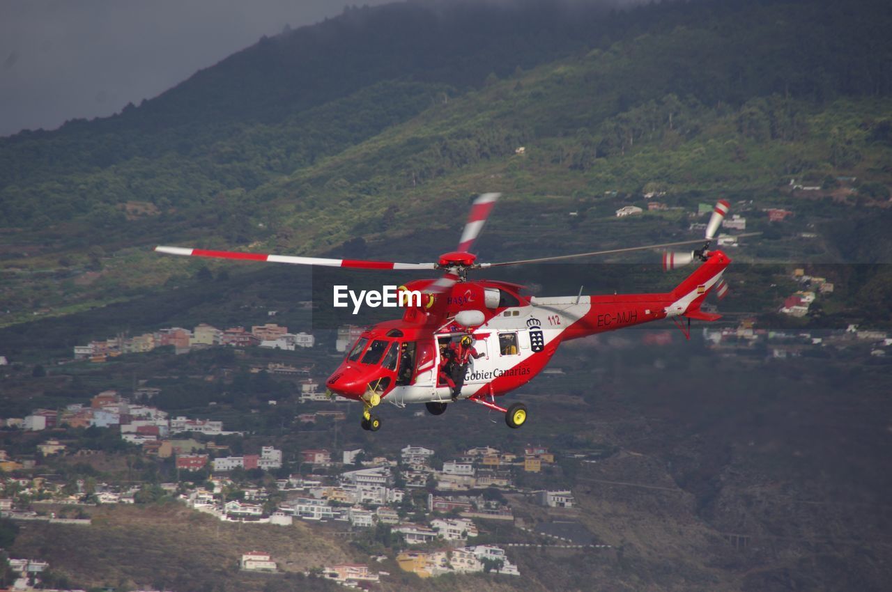 HIGH ANGLE VIEW OF AIRPLANE FLYING ABOVE MOUNTAIN