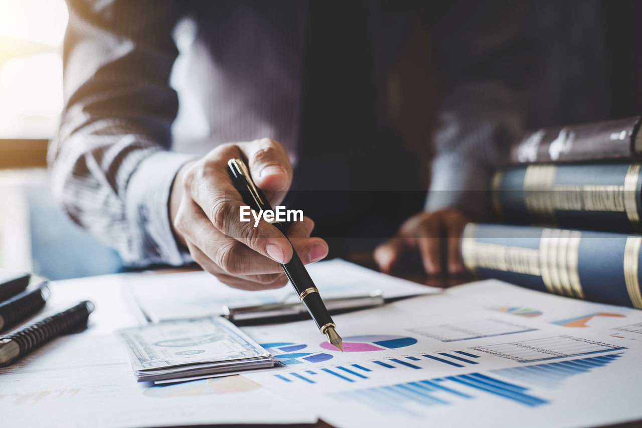 Midsection of businessman working on graph at office