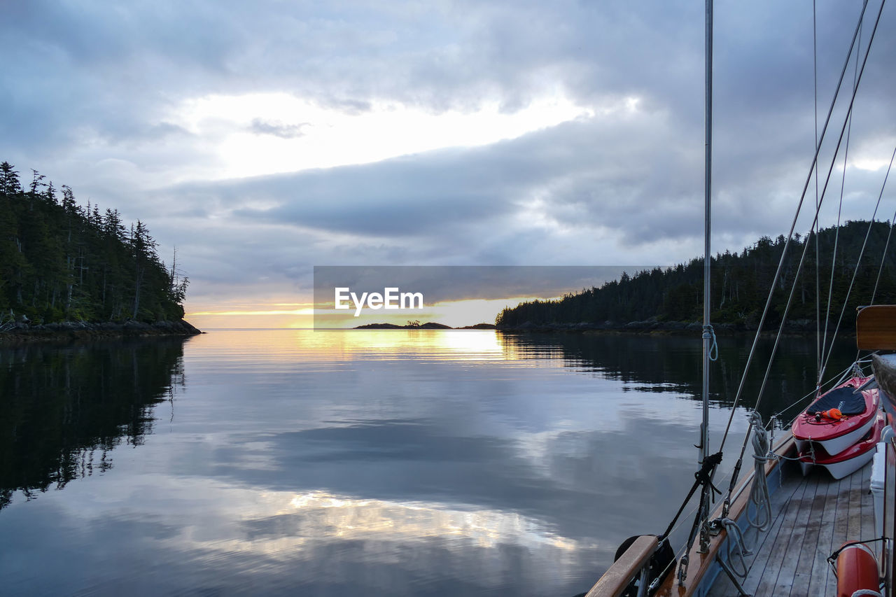 BOATS SAILING ON LAKE AGAINST SKY AT SUNSET