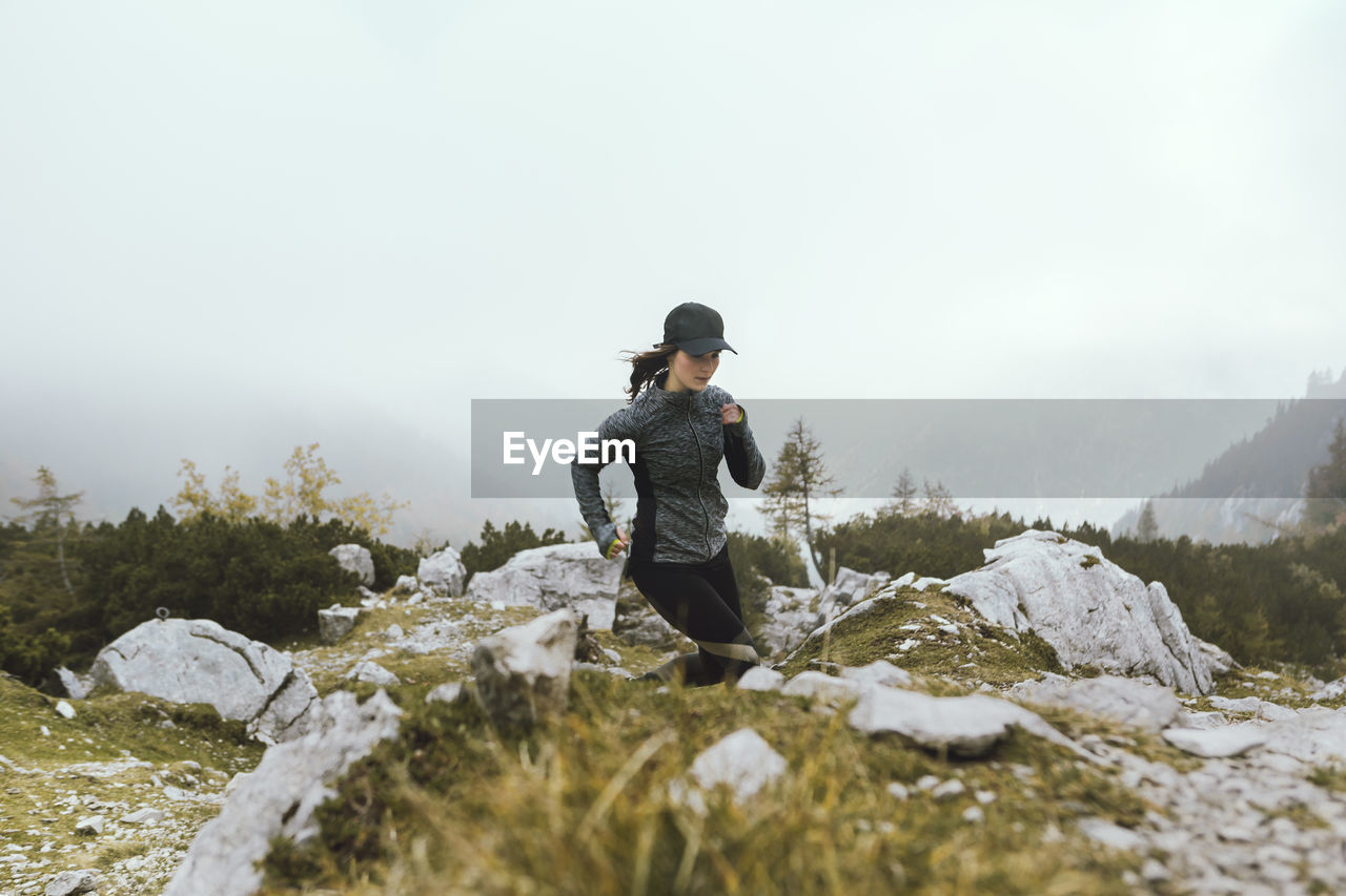 Young woman running on field during foggy weather