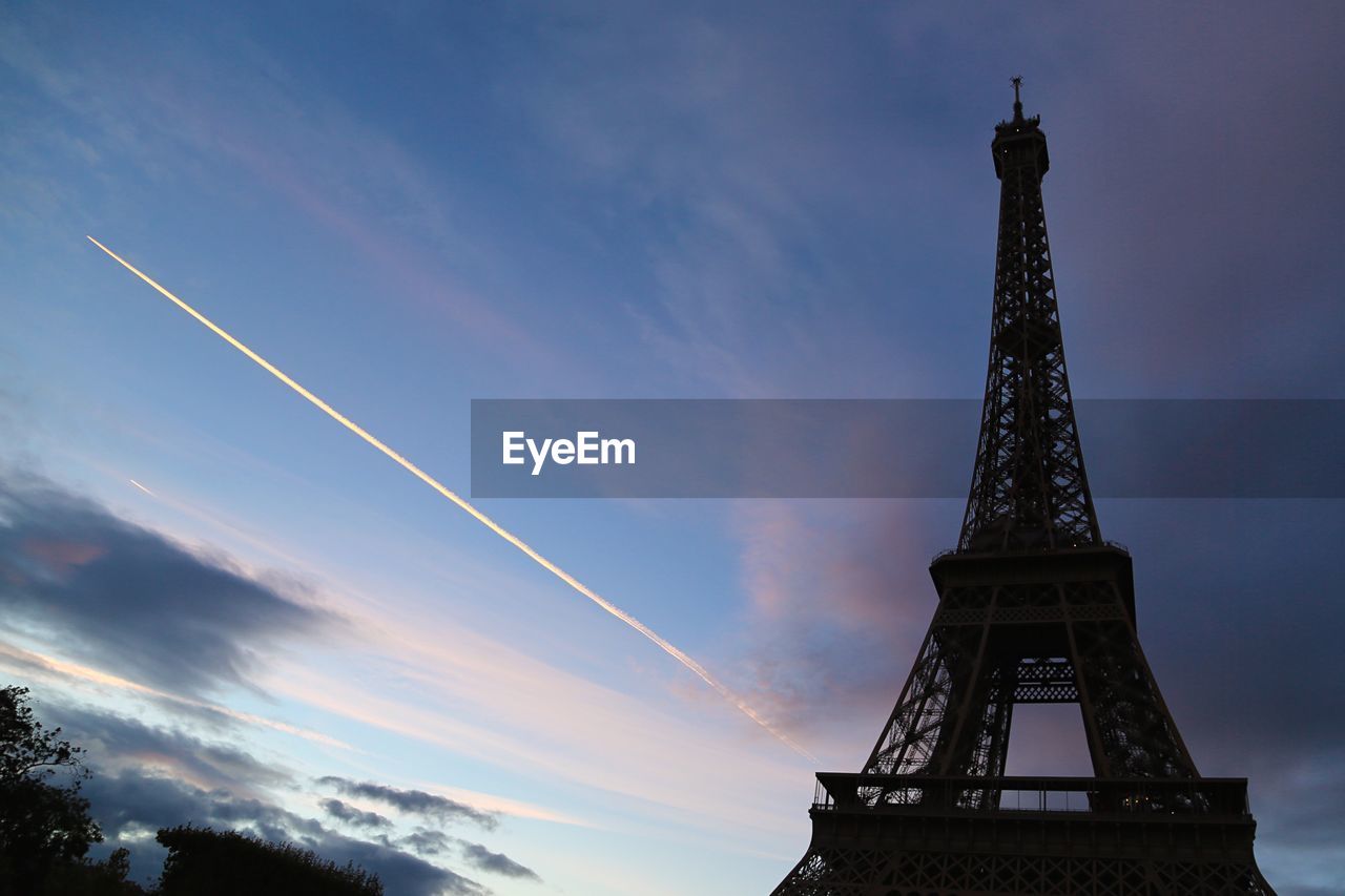 Low angle view of eiffel tower against vapor trail in sky