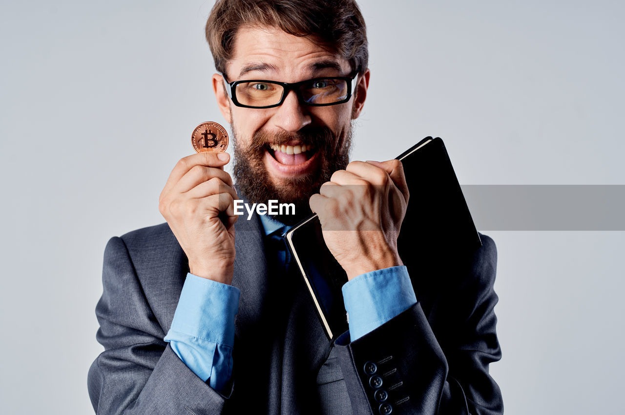 adult, eyeglasses, men, one person, glasses, businessman, studio shot, business, portrait, indoors, facial hair, beard, formal wear, emotion, front view, gray, happiness, young adult, smiling, communication, person, facial expression, vision care, conversation, necktie, looking at camera, gray background, copy space, menswear, technology, clothing, fun, looking, white-collar worker, positive emotion, office, professional occupation, business finance and industry, cheerful, waist up, button down shirt, humor, corporate business, eyewear, brown hair, occupation