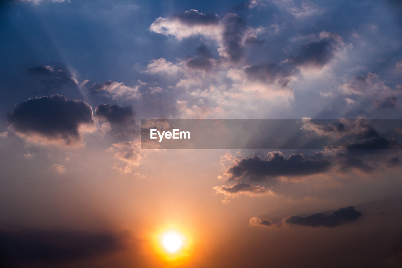 LOW ANGLE VIEW OF SUN STREAMING THROUGH CLOUDS