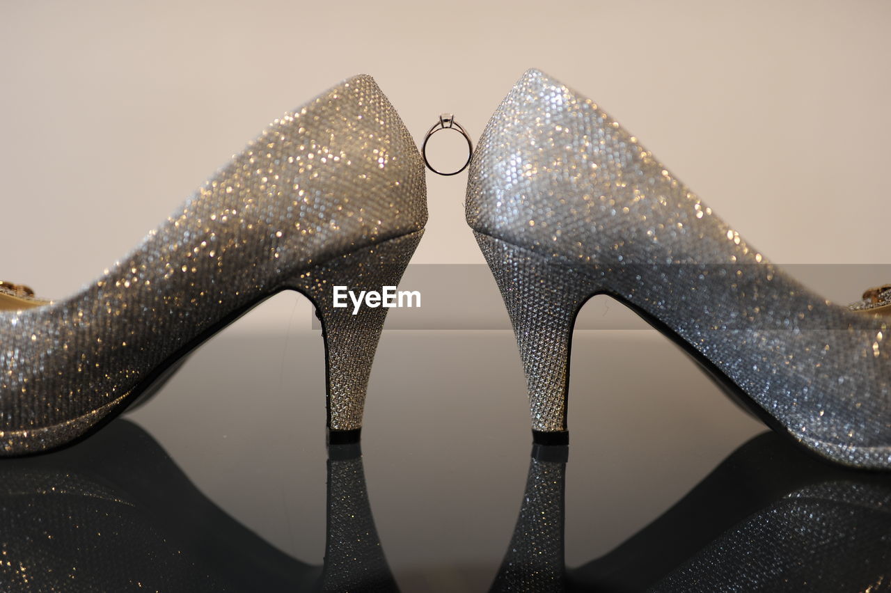 Close-up of diamond ring amidst shining shoes on table