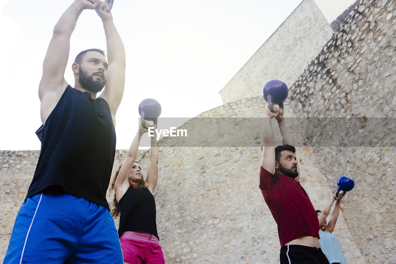 Athletes lifting a kettelbell crossfit weights in an urban enviroment.